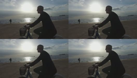 夕阳西下，成熟的女人在海边骑自行车高清在线视频素材下载