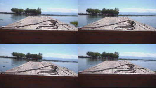 从一艘木船的前面，一个大的湖与山和多云的天空的背景。高清在线视频素材下载