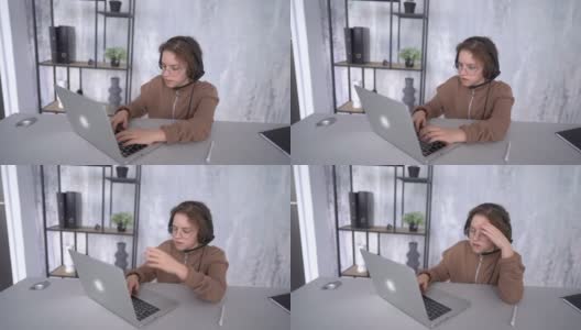 在远程学习时，一个戴着耳机看着笔记本电脑屏幕的女孩的脸。一个女生在网上上课高清在线视频素材下载