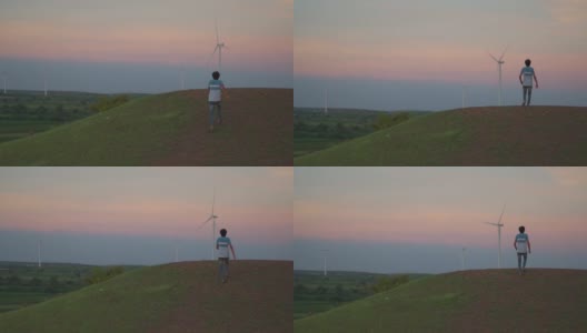 日落时分，印度古吉拉特邦万卡纳，一名印度男子在风电场的风车前奔跑。环境可持续性的背景。希望绿色能源取代化石燃料。高清在线视频素材下载