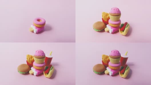 各种快餐特写的微缩模型。人类的手在明亮的粉红色背景上铺上美国快餐的小型玩具。4k延时搞笑微距视频。高清在线视频素材下载
