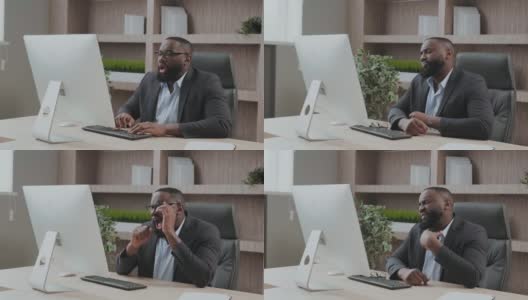 疲惫的非洲裔美国男性员工在办公室的椅子上打哈欠伸懒腰，在工作场所不堪负荷的工作，疲惫的混血儿年轻员工表示在漫长的一天后感到疲劳，睡眠不足高清在线视频素材下载