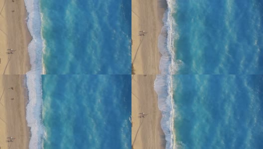 希腊莱夫卡达的米洛斯海滩。从上往下看，金色的沙滩和荧光的绿松石色的海浪。在日落时分欣赏夏日美景的人们高清在线视频素材下载