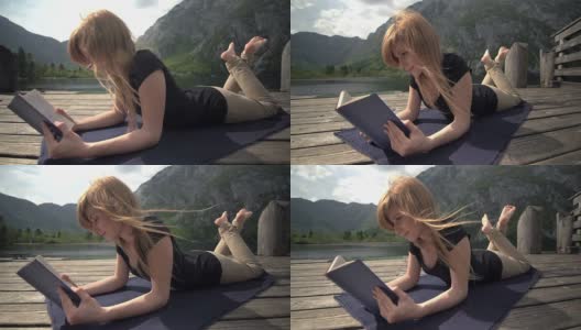 年轻女子在山腰的湖边看书高清在线视频素材下载