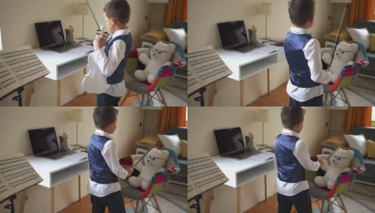 一个在家练习小提琴的男孩正在给他的泰迪熊演奏音乐高清在线视频素材下载
