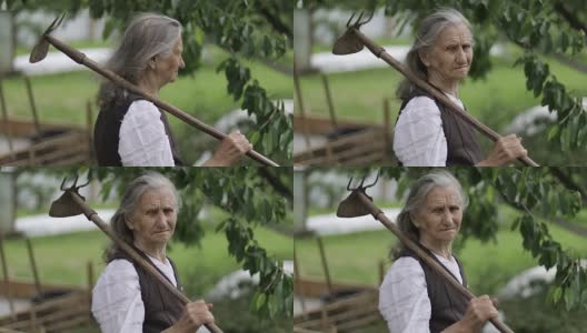 一个肩上扛着锄头的老妇人的肖像。高清在线视频素材下载