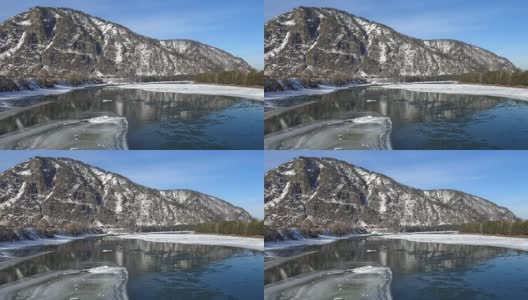 冬季鸟瞰阿尔泰河卡顿，背景为水中浮冰和群山高清在线视频素材下载