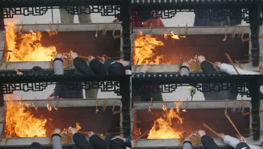 慢镜头火和香烟在中国传统寺庙，祈祷者把燃烧的香放入香炉，4K视频。高清在线视频素材下载