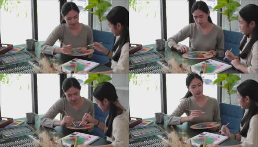 年轻的亚洲老师在美术课上和亚洲女孩一起画画。高清在线视频素材下载