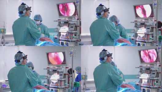 进行手术的专业外科医生。穿着特殊衣服和技术设备的医生看着显示手术区域的屏幕。高清在线视频素材下载