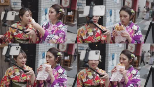 年轻的女性朋友穿着和服在街上吃面包，为了拍视频高清在线视频素材下载