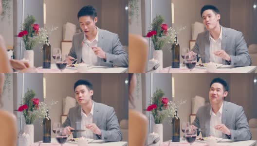 亚洲年轻情侣共进晚餐庆祝情人节。迷人浪漫的新婚男女在家里的厨房里举行晚会，在餐桌上吃结婚纪念日的食物。高清在线视频素材下载