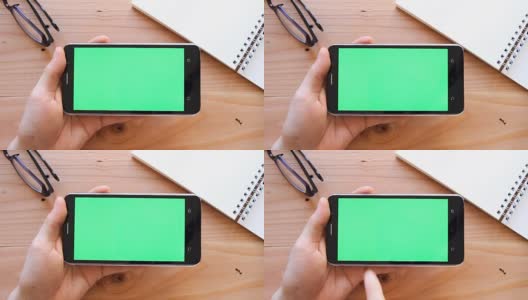 手用手机与绿色屏幕上的木制办公桌顶视图高清在线视频素材下载