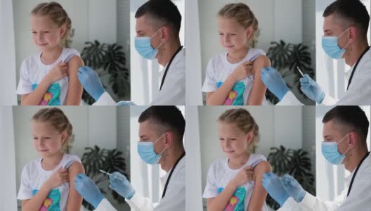 一名戴着医用口罩的医生在一个孩子的肩膀上注射。疫苗接种对冠状病毒。COVID-19疫苗。医生给孩子打了疫苗。一个小女孩在打流感疫苗。高清在线视频素材下载