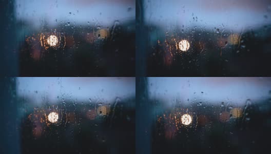 晚上，雨滴沿着玻璃流下来。窗外的城市灯火通明。拍摄特写镜头高清在线视频素材下载