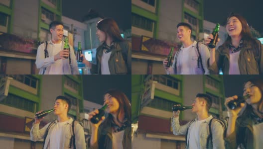 亚洲帅哥情侣一起喝酒开派对。在城市里旅游的青年男女，在假期里一起拿着一瓶啤酒，在漆黑的夜晚在路上度过时光。高清在线视频素材下载
