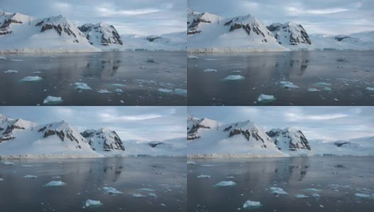 南极洲。南极洲雪山和冰雪海岸的景观。美丽的蓝色冰山与镜面反射漂浮在开放的海洋。严酷大陆上的冰川。高清在线视频素材下载