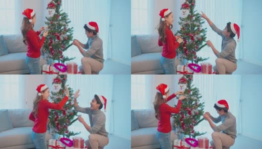 亚洲夫妇在家里用幸福装饰圣诞树。有魅力的女人和男人在房子的客厅里一起庆祝节日圣诞节感恩节聚会，感到高兴和兴奋高清在线视频素材下载