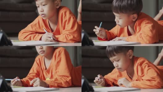 穿着橙色衬衫的男孩正专注于在线学习。高清在线视频素材下载