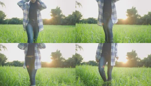 穿着黑色靴子的女农民的脚小心翼翼地走在高高的草地上，背靠着阳光，穿着胶靴的女农民下半身走路，以美丽的绿色大自然为背景徒步高清在线视频素材下载