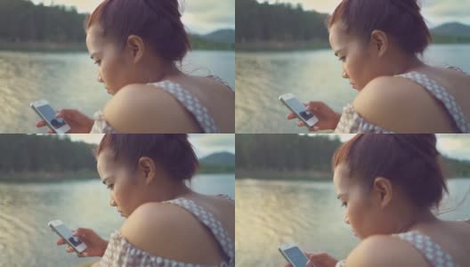 亚洲女性在河边使用智能手机的慢镜头高清在线视频素材下载