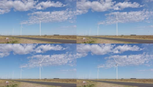 风力发电场建在路边的田地里。风车缓缓转动，蓝天飘着朵朵白云高清在线视频素材下载
