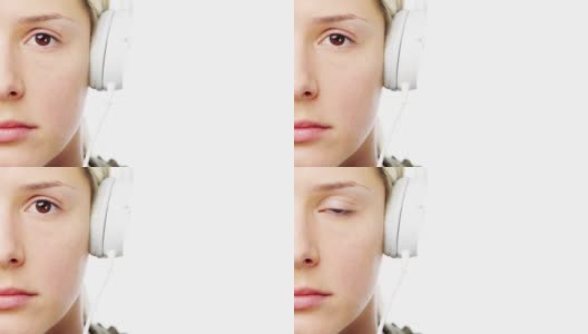 一个年轻女子戴着耳机在白色录音室背景下拍摄的4k视频片段高清在线视频素材下载