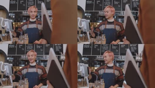 一名男子在咖啡馆为顾客点餐时使用数码平板电脑高清在线视频素材下载