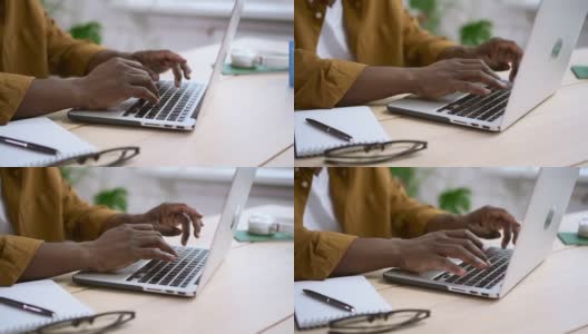 黑人在办公桌上用白色笔记本电脑工作，背景是办公室在家里的Spbas高清在线视频素材下载
