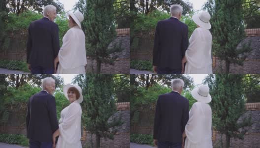 后视镜深情的老夫妇手牵手站在户外，新娘扔新娘捧花的慢镜头。激动的白人男女结婚了。传统和爱的观念。高清在线视频素材下载