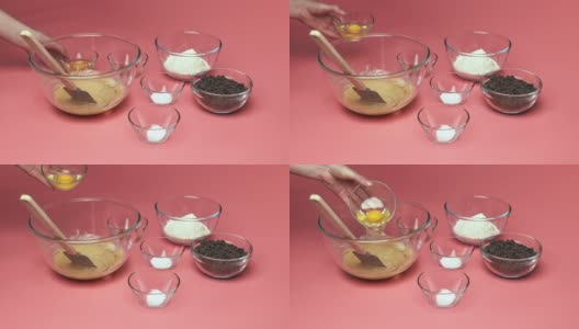在粉色背景的玻璃碗中加入/混合巧克力片饼干配料:红糖、白糖、巧克力片、鸡蛋、面粉、黄油、香草精、小苏打、4K盐。高清在线视频素材下载