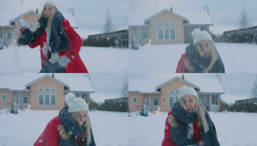 快乐的年轻微笑的女人扔雪球，并被一个击中。穿红外套的女孩和她的伴侣享受冬天。田园小屋后院里的一天。高清在线视频素材下载