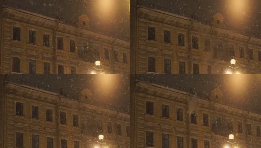 人把雪从屋顶上扔下来。晚上城里下大雪高清在线视频素材下载
