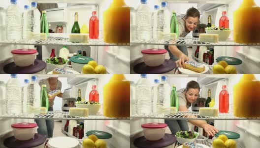 女人打开冰箱，咬了一口甜甜圈高清在线视频素材下载