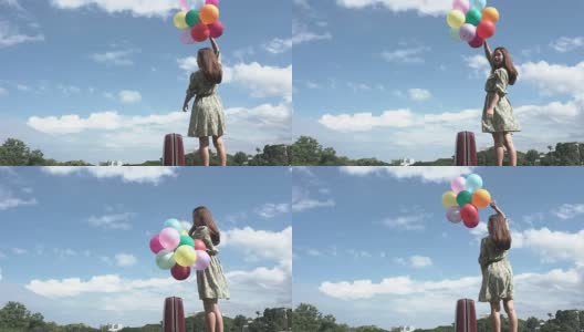 一个美丽的女孩在户外拿着一个气球，背景是山脉和河流。想想亚洲女孩的开朗。高清在线视频素材下载