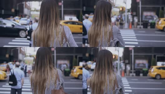 年轻美丽的女人在纽约过马路的背影，美国。女性看乘坐的汽车和出租车高清在线视频素材下载