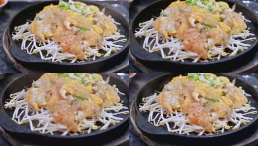 特写慢镜头的泰国食物或街头食物在热盘在餐厅服务。用面粉和豆芽炒生蠔，盛于热板内。高清在线视频素材下载