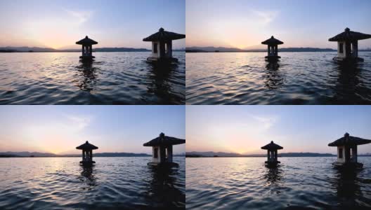 美丽的日落风景在西湖，中国，杭州，橘色的黄昏天空和宁静的水与传统的亭台楼阁在湖中，闪烁的涟漪，超级慢的动作。高清在线视频素材下载