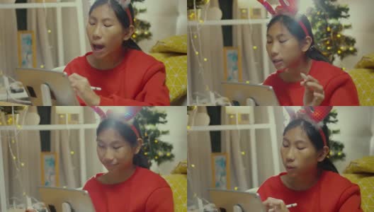 快乐的亚洲女孩穿着红色的毛衣，唱歌和绘画的数字平板电脑在家里的圣诞装饰，生活理念。高清在线视频素材下载