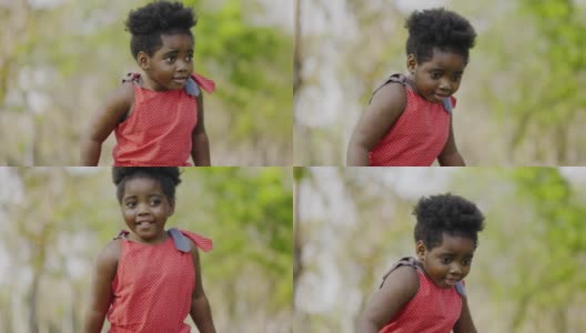非裔美国女孩穿着红色圆点衬衫快乐地站在花园里夏天。学龄前儿童快乐成长。周末活动快乐家庭生活理念。概念儿童节高清在线视频素材下载
