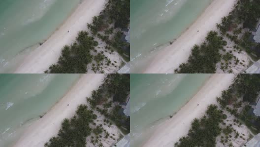 从空中俯瞰白色沙滩上的蓝色海洋，在亚洲的一个度假胜地，沿着海滩的棕榈树高清在线视频素材下载
