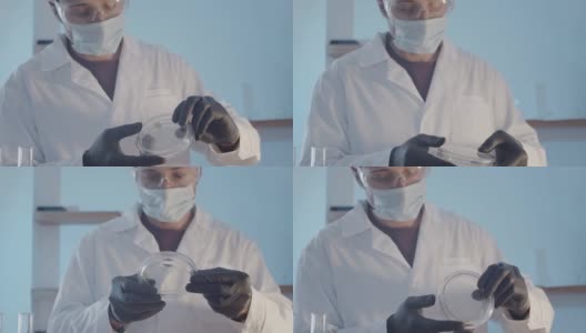 戴着防护橡胶手套和眼镜的博士研究员在培养皿中近距离观察一件人工制品。科学实验室的研究工作。高清在线视频素材下载