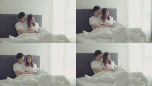 亚洲丈夫和怀孕的妻子会在卧室里一起读书给孩子听。高清在线视频素材下载