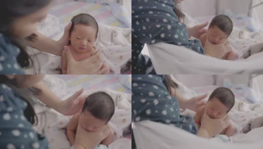 亚洲妈妈在给宝宝喂奶后，用奶瓶喂奶，帮助宝宝消化食物。高清在线视频素材下载