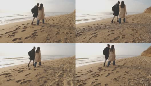 在多云的日出或日落时，幸福的情侣漫步在野生的海滩上高清在线视频素材下载