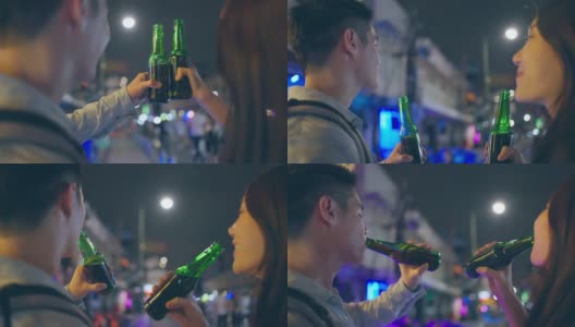 亚洲帅哥情侣一起喝酒开派对。在城市旅游的年轻男女在假期的夜晚一起在路上碰碰啤酒高清在线视频素材下载