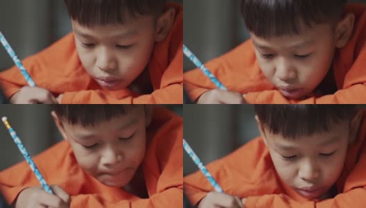穿着橙色衬衫的小男孩正在画画。高清在线视频素材下载