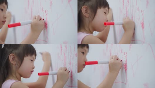 亚洲小女孩喜欢在客厅的白墙上作画。可爱的小朋友们在家里愉快地画画、涂色，享受着节日的创意活动。高清在线视频素材下载