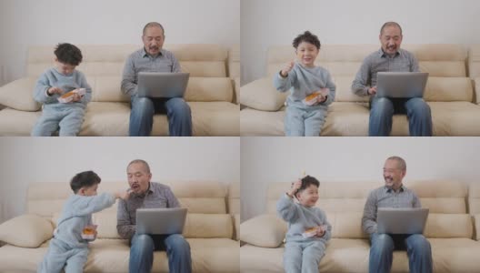 父子俩在沙发上用笔记本电脑高清在线视频素材下载