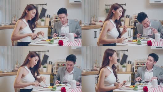 亚洲年轻情侣共进晚餐庆祝情人节。迷人浪漫的新婚男女在家里的厨房里举行晚会，在餐桌上吃结婚纪念日的食物。高清在线视频素材下载